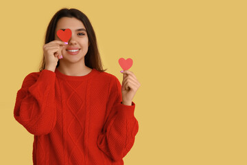 Wall Mural - Happy young girl with red paper hearts on yellow background. Valentine's Day celebration