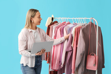 Sticker - Female stylist with laptop and on rack against blue background