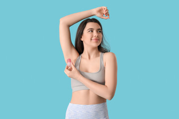 Sticker - Beautiful young woman using crystal deodorant on blue background