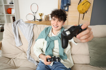 Poster - Male student with game pads sitting on sofa at home