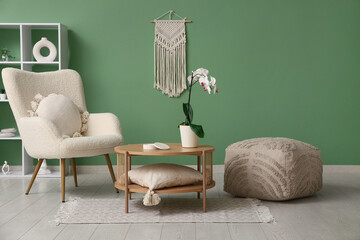 Wall Mural - Armchair with pillow, pouf and coffee table with orchid in living room