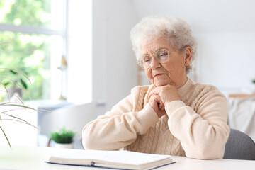 Canvas Print - Senior woman reading Bible at table in living room