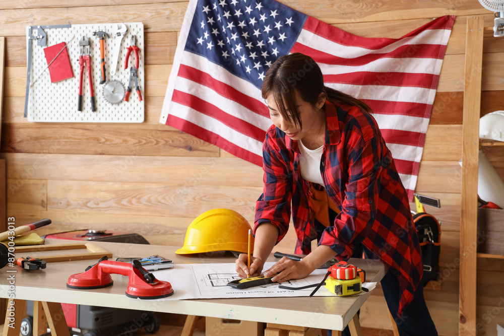 Female Asian worker with house plan in workshop. Labour Day celebration