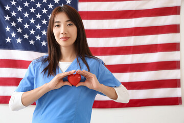 Sticker - Female Asian doctor with heart against USA flag. Labour Day celebration