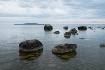 Sticker - Tranquil seascape with large rocks in the foreground and an island in the distance in Ontario Canada