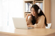© Monster Ztudio - Young asian woman wearing headset while working on computer laptop at house. Work at home, Video conference, Video call, Student learning online class