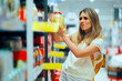© nicoletaionescu - Woman in a Supermarket Checking the Label on a Jar of sauerkraut. Customer verifying the expiration date on a product in a store