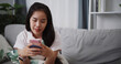 © Johnstocker - Portrait of Carefree young woman playing social media by smartphone on sofa at home ,Lifestyle with device technology