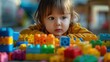 © bird_saranyoo - Close-up of a toddler playing with a brick, concentrating on their creation.
