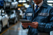 © Phichitpon - Smiling, friendly man in car seller standing in auto salon and using digital tablet to check on new messages customers post on internet, smiling at camera