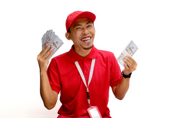 Asian delivery man holds Dollars banknotes in his hand, isolated on white background. Concept of financial success, windfalls, e-commerce, delivery services, and positive financial outcomes