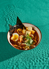 Canvas Print - Delicious Bowl of Ramen with Tofu, Egg, and Seafood on Vibrant Green Background