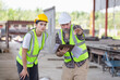 © JU.STOCKER - Engineer and foreman worker checking project at building site, Engineer and builders in hardhats discussing on construction site, Teamwork concepts