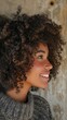 © Hryhor Denys - A close up of a beautiful black woman with Afro hair smiling while wearing a cozy sweater