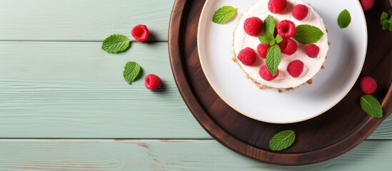 Leinwandbilder - Top-down view of raspberry cheesecake on a plate with mint leaves, offering copy space image.