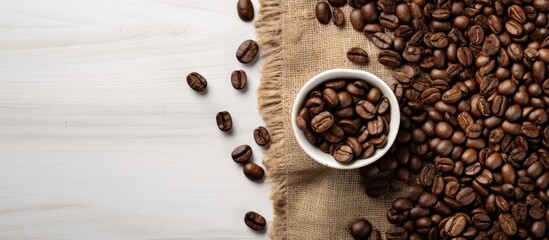 Fototapete - On a white table background, there is a top-down view of roasted coffee beans next to a sack, with room for additional content in the image.