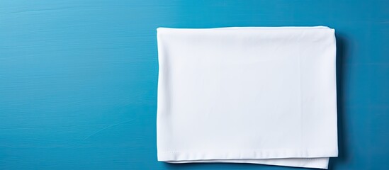 Poster - A picture showing a clean white plate and a soft cloth napkin set against a blue background provides a food-themed copy space image, ideal for menus and recipe books, featuring a table setting in a