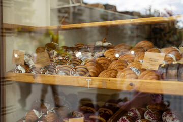 A variety of fresh pastries in the bakery window. Sweet big Croissant on shelf show for sale. Close up of appetizing golden croissants in cafe on shop window.