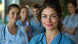 © ifoto - A smiling nurse in blue scrubs stands with her medical team behind