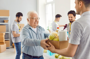 Poor old man gets food aid. Senior citizen who belongs to vulnerable social group gets help at charity organization. Thankful grateful aged man takes grocery box at community centre. Donation concept