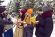 © Studio Romantic - Happy friends with hot drinks in paper cups chatting and having fun outdoors in winter park. Man pours tea or coffee from thermos into disposable paper cups. People, season, drinks and winter concept.