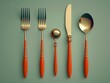 © Andrea Marongiu - Set of golden cutlery with orange handles is lying on a green background, creating an elegant and minimalist aesthetic. The image evokes a sense of sophistication and modern design