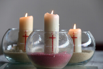 Three church candles in sand.