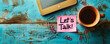 © Bartek - Inviting Workplace Concept with Let's Talk! Message on Pink Sticky Note, Coffee, Tablet, and Paper Clips on Wooden Desk