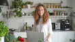 © Valerii Apetroaiei - Young woman enjoys healthy cooking in her modern kitchen, using a laptop for recipes. Surrounded by fresh vegetables and herbs, she cultivates a vibrant and nutritious lifestyle at home.