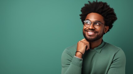 Portrait of a smiling man wearing glasses and a green sweater, looking away confidently on a green background. This upbeat and stylish image captures positivity and modern fashion.