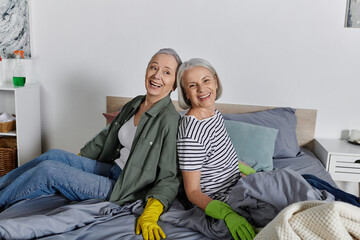 Two mature women in casual attire clean their modern apartment.