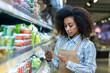© Liubomir - A grocery store employee in an apron checks the inventory on the shelves using a tablet. The worker appears focused and attentive, ensuring the store is well-stocked and organized for customers.