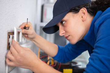 young brunette woman repairs an electric socket