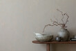 © FollowTheFlow - Minimalist composition of living room interior with copy space, wooden consola, ceramic bowl, gray vase with branch, cup, beige wall and personal accessories. Home decor. Template.
