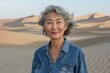 © CogniLens - Portrait of a satisfied asian woman in her 60s sporting a versatile denim shirt isolated in backdrop of desert dunes
