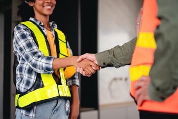 A construction worker shakes hands with a woman wearing a yellow vest