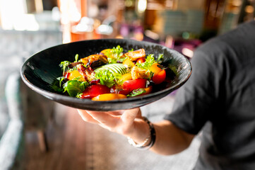 Sticker - A vibrant salad with fresh greens, tomatoes, and grilled vegetables served on a dark plate.