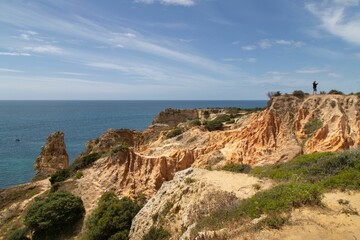 Sticker - Scenic view of a sandy beach with rocky cliffs and clear blue water in Algarve, Portugal