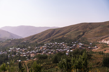 A small town is nestled in the mountains, with houses and trees surrounding it