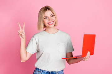 Sticker - Photo of toothy beaming woman with bob hairdo dressed gray t-shirt hold laptop showing v-sign symbol isolated on pink color background