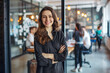 © Jacek - Portrait of a smiling business woman standing with her arms crossed in a modern office.