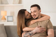 © New Africa - Woman hugging her happy boyfriend on sofa at home