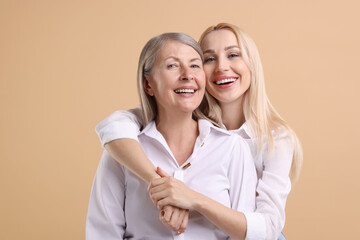 Wall Mural - Family portrait of young woman and her mother on beige background