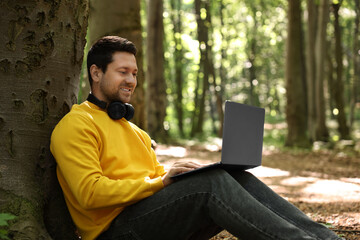 Canvas Print - Smiling traveler working with laptop outdoors. Remote job