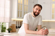 © New Africa - Happy young man with glass of water in kitchen at morning