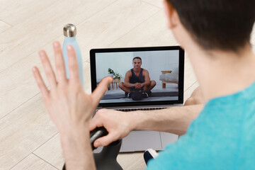 Wall Mural - Online fitness trainer. Man having video chat via laptop indoors, closeup