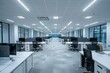 © Rayhanbp - An empty modern office with white walls and light grey carpeted flooring, featuring rows of desks arranged side by side. The space is well lit from the ceiling lights above each desk.