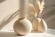 © Rayhanbp - Beige ceramic vase with circular pattern on a white table, another vase and pampas grass nearby, in a minimalist style