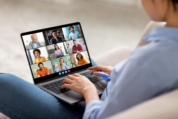 Aufkleber - The image shows a woman sitting on a couch, participating in a video conference on a laptop computer. Her laptop is open and shows a grid of nine video feeds, each featuring a different person.