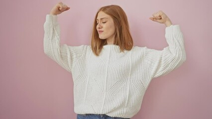 Sticker - Smiling young redhead woman confidently standing isolated over pink background, wearing sweater, flexing her strong arms muscles, embodying a successful fitness lifestyle concept.